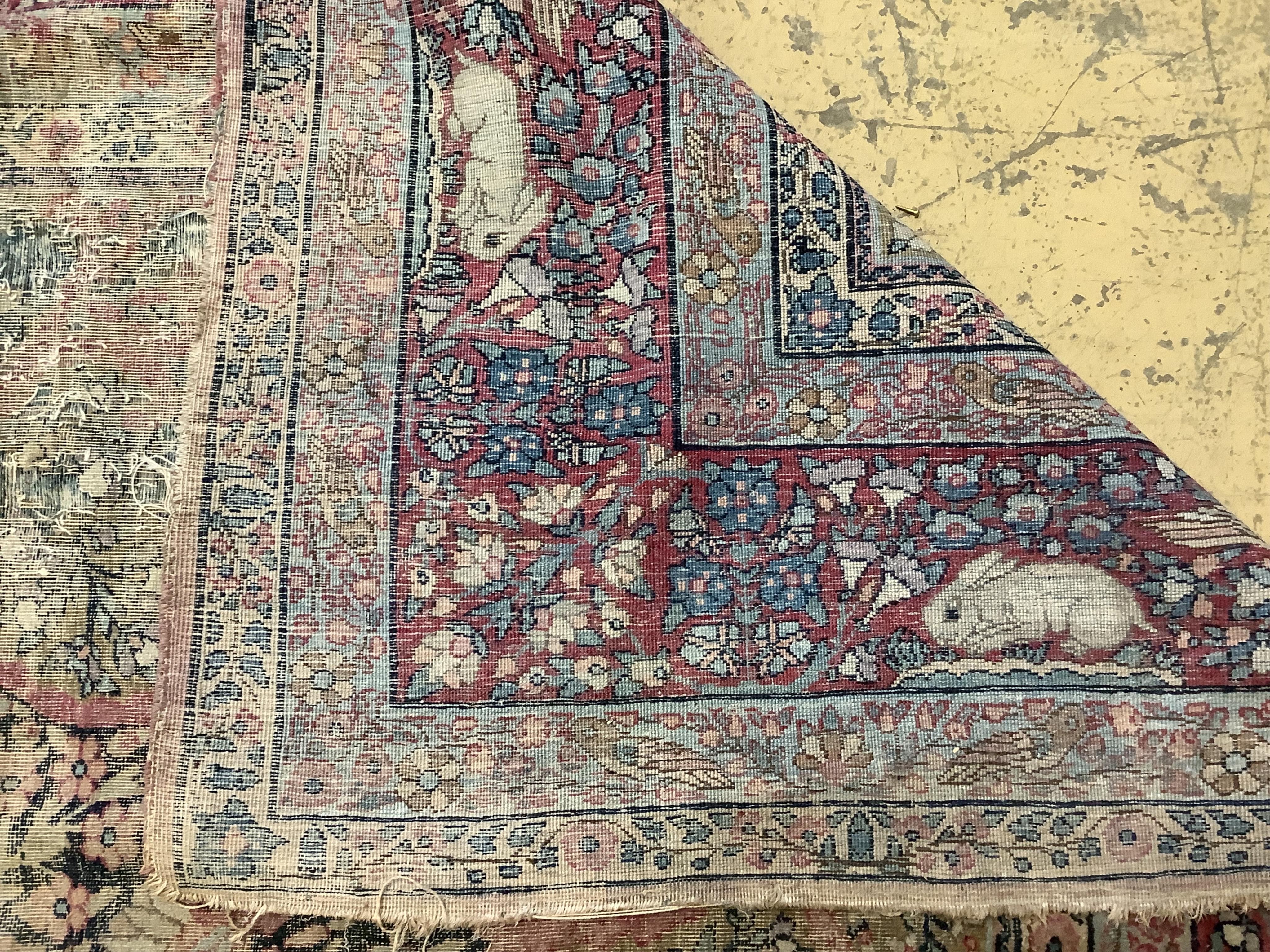 An antique Kirman ivory ground pictorial carpet (severely worn), 348 x 265cm